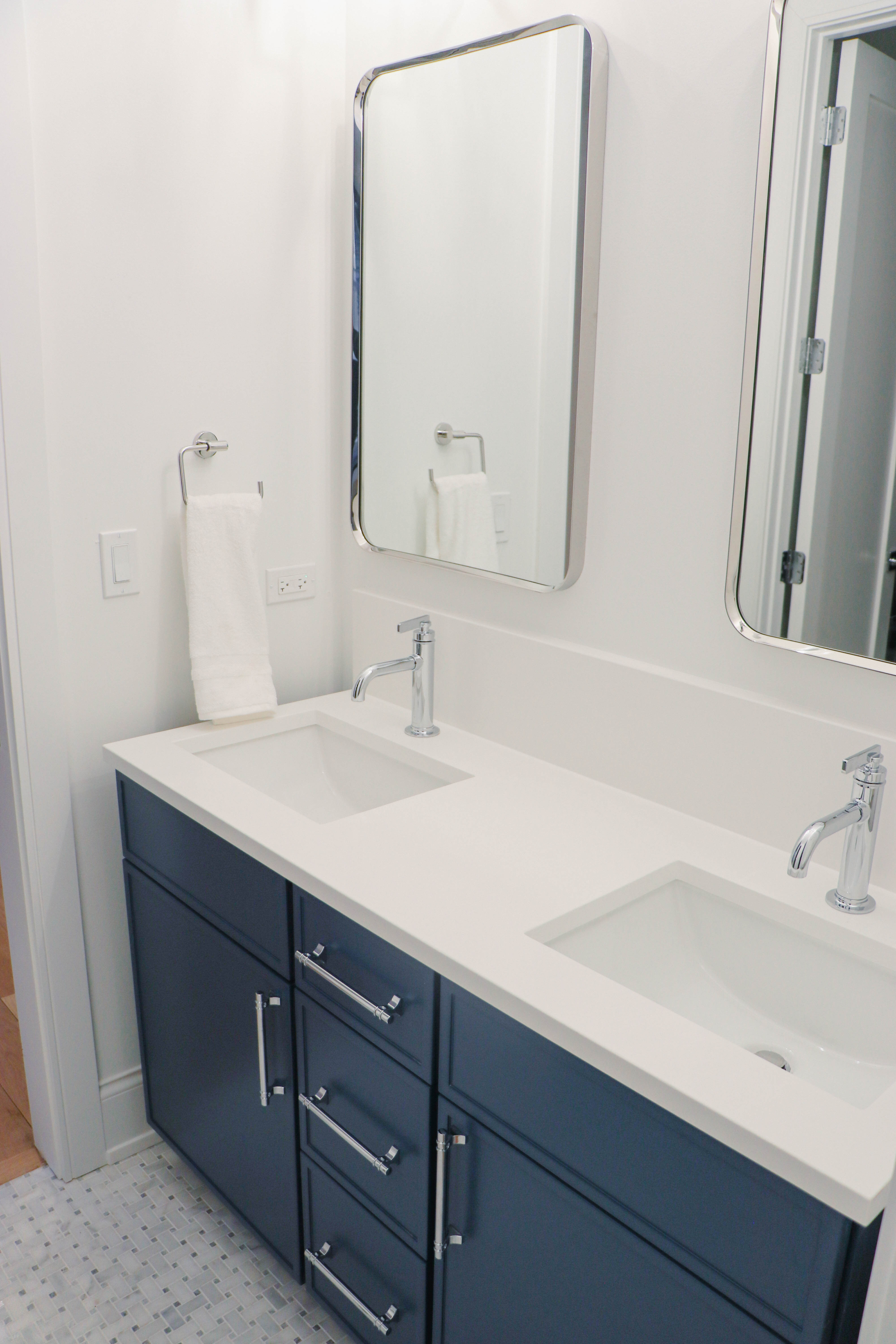 Magnolia bathroom — navy vanity, marble mosaic floor, chrome fixtures