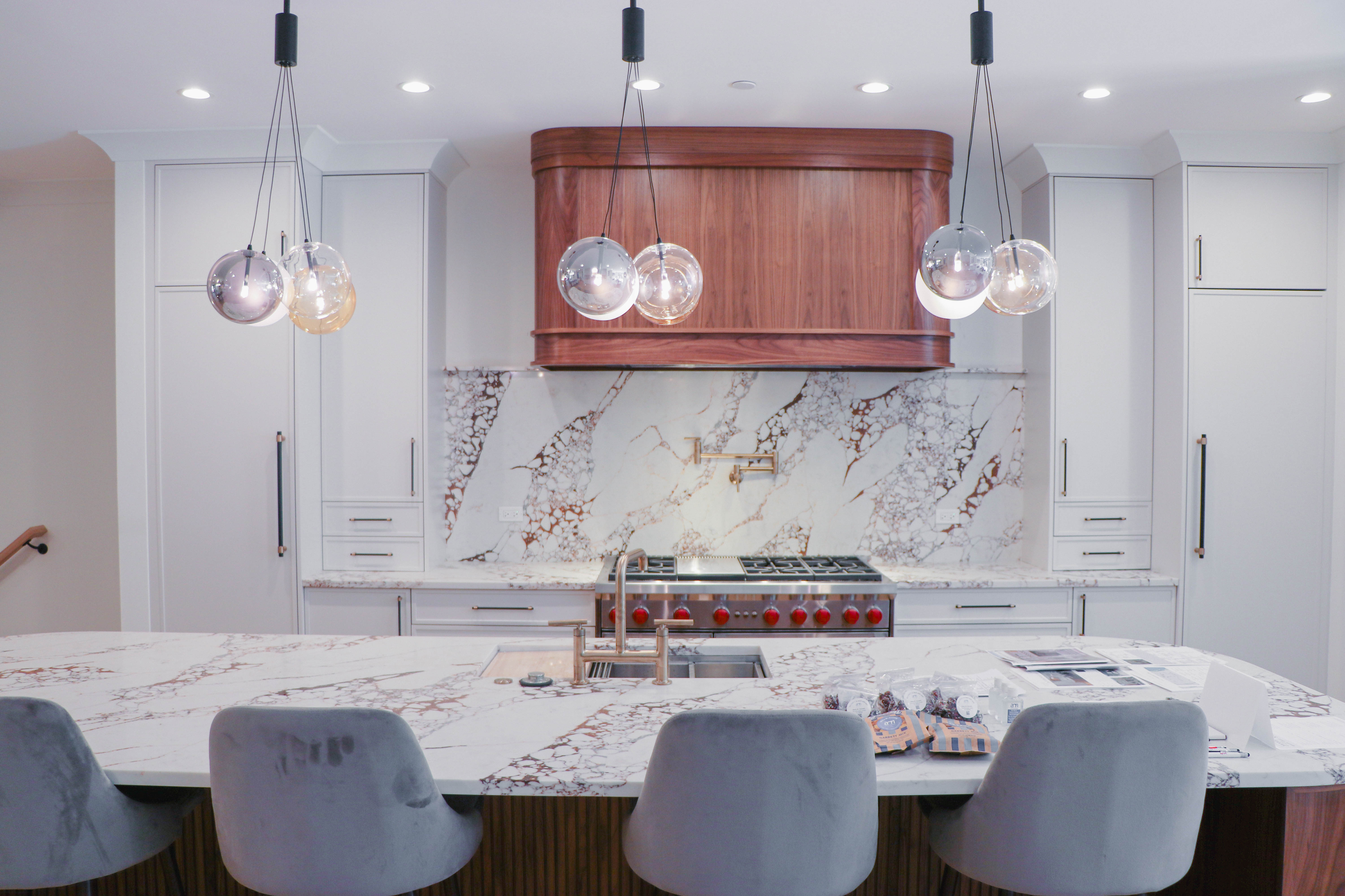 Magnolia kitchen — marble backsplash, custom hood, designer pendants